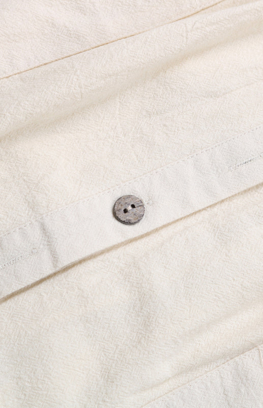 Cream-colored solid color short sleeve shirt dress fabric with a button detail