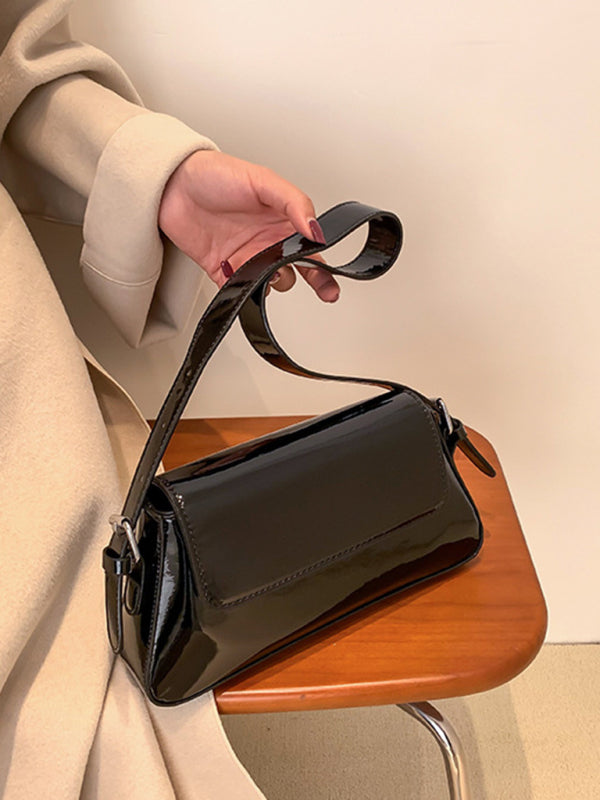 Modische Damen-Schultertasche aus Lackleder mit Baguette-Struktur und glänzendem Finish, die unter dem Arm getragen wird 