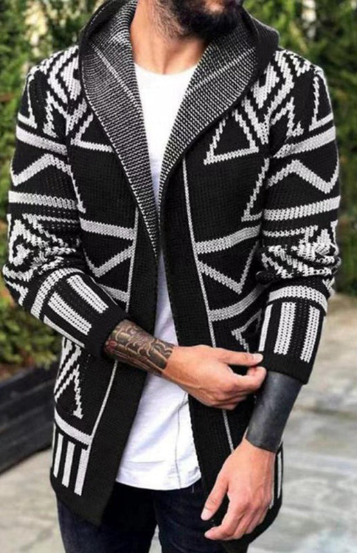 A man wearing a black and white long jacquard knitwear cardigan sweater with a lapel collar and geometric pattern over a white t-shirt.