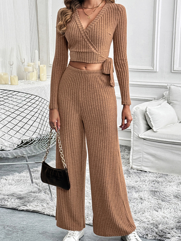 Autumn and winter long-sleeved solid color texture basic versatile ladies two-piece suit with deep V neckline and tied waist, worn by a woman holding a black handbag, standing in a modern living room.