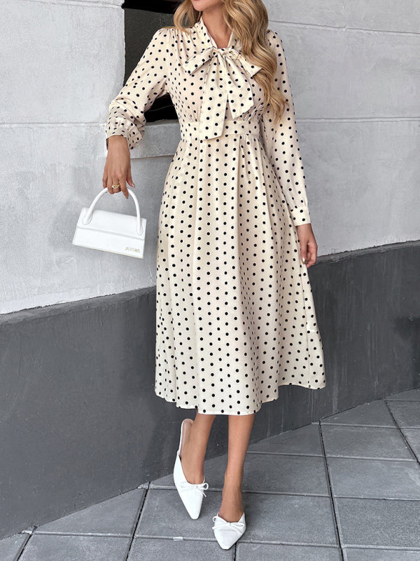 Robe élégante mi-longue à pois, col à nœud papillon, manches longues et taille marquée. 