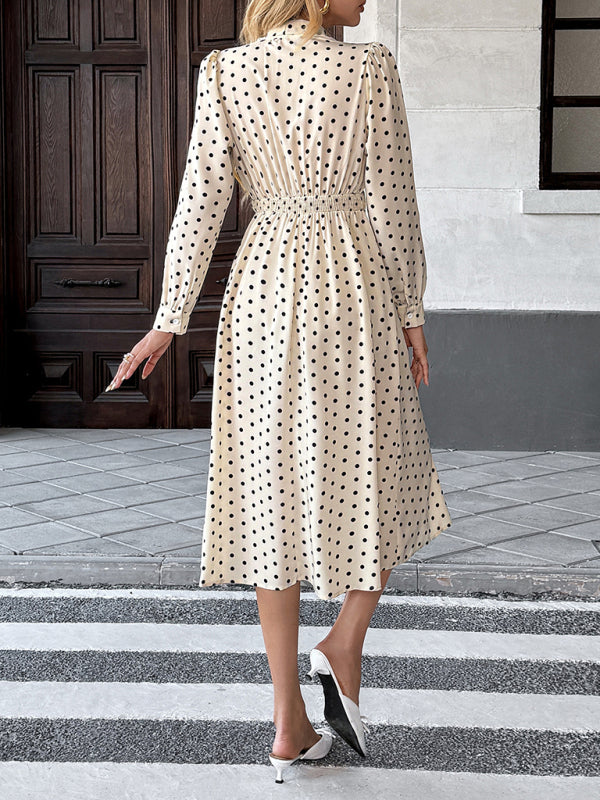 Robe élégante mi-longue à pois, col à nœud papillon, manches longues et taille marquée. 