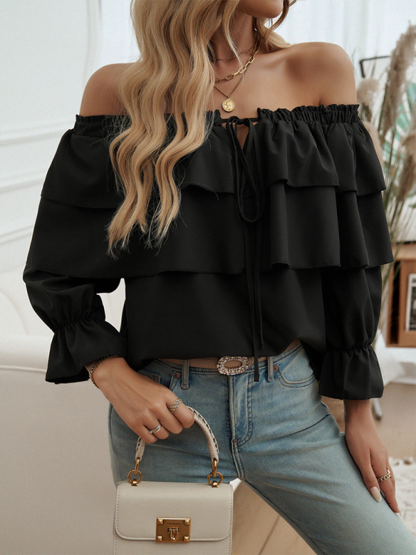 Woman wearing a black off-the-shoulder ruffled blouse with jeans, showcasing a loose-fitting pleated balloon sleeve top