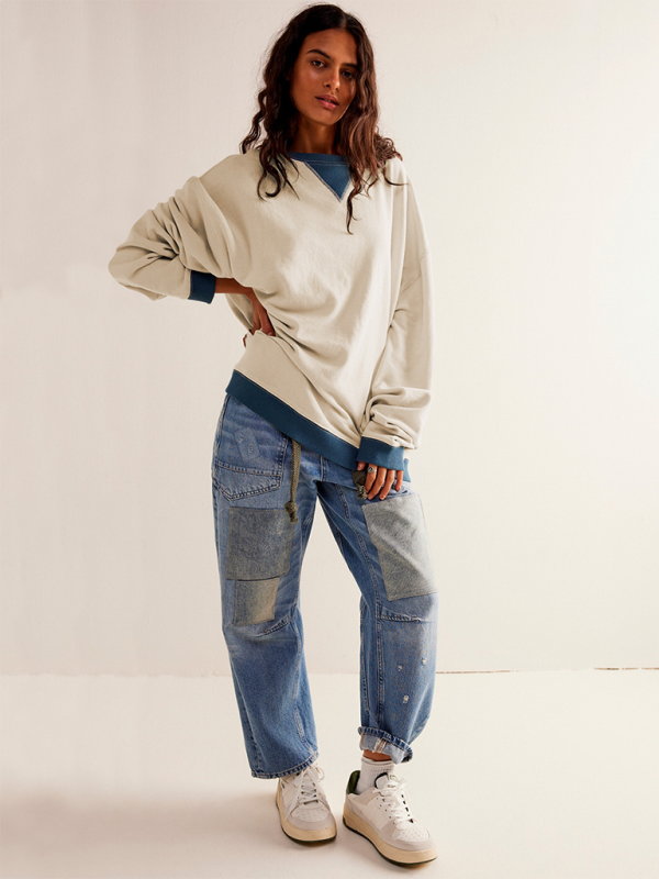 Woman wearing oversized solid color round neck sweatshirt and patchwork jeans outfit