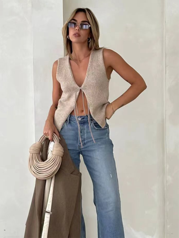 Woman wearing a beige tie-front knit vest with wide-leg jeans, showcasing weaving type style