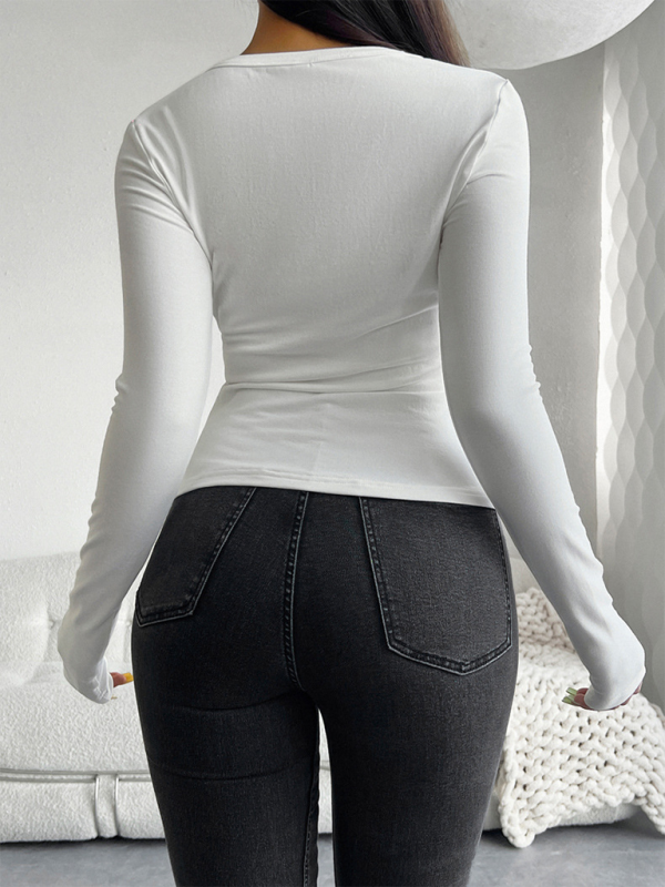 White long-sleeved V-neck button-front top paired with dark jeans for a stylish look