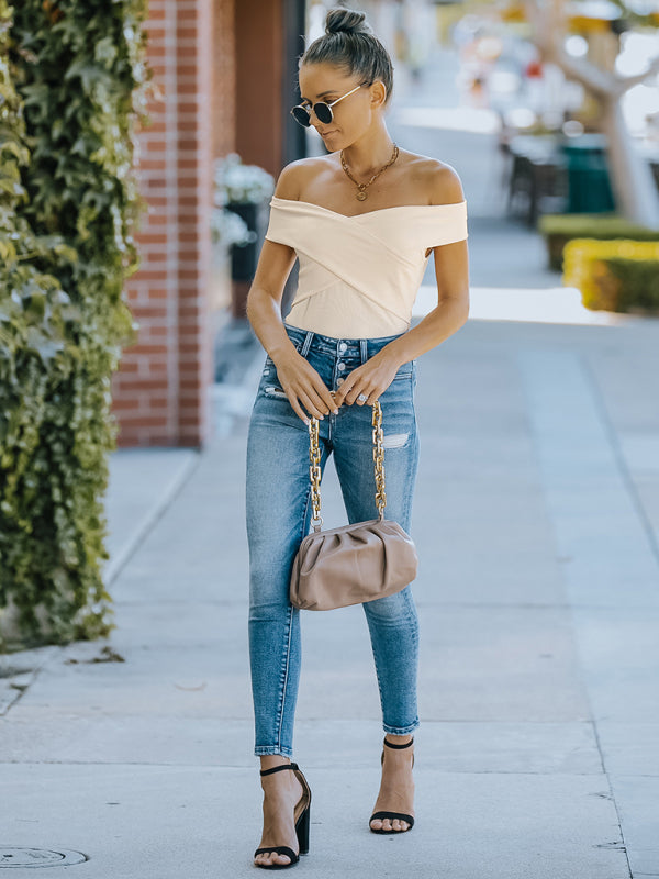Woman modeling fashion skinny off-shoulder top with slight elasticity, jeans, and heels